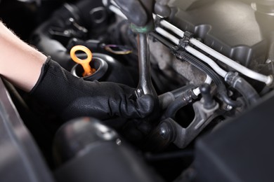 Photo of Auto parts. Professional mechanic with torque wrench fixing car indoors, closeup