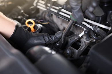 Photo of Auto parts. Professional mechanic with torque wrench fixing car indoors, closeup