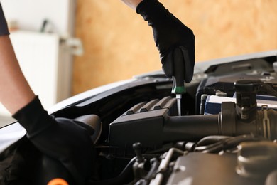 Photo of Auto parts. Professional mechanic with screwdriver fixing car indoors, closeup