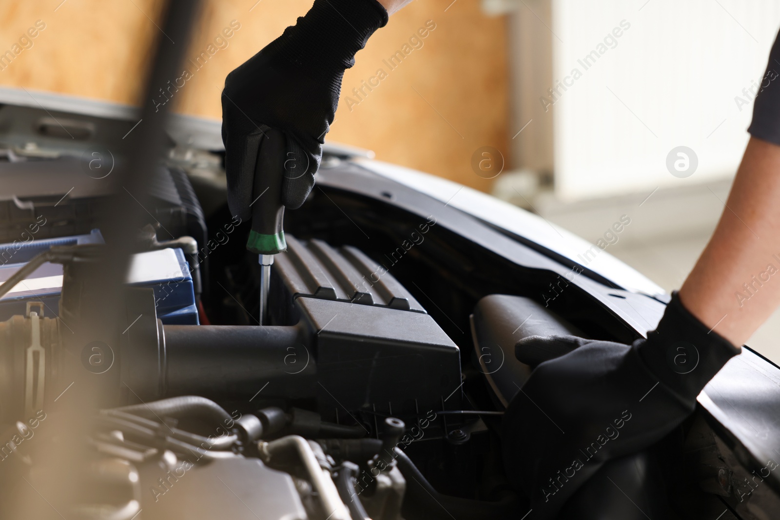 Auto parts. Professional mechanic with screwdriver fixing car indoors, closeup Photo of Auto parts. Professional mechanic with screwdriver fixing car indoors, closeup