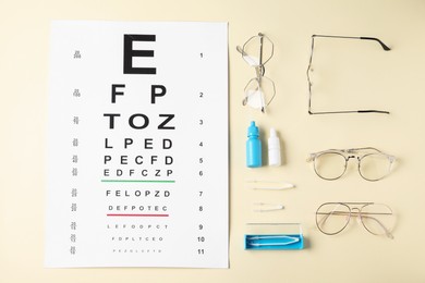 Photo of Vision test chart, glasses, tweezers and bottles of medical drops on beige background, flat lay