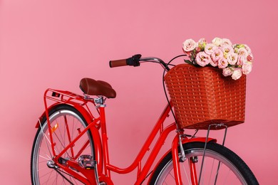 Photo of Bicycle with basket of beautiful flowers on pink background