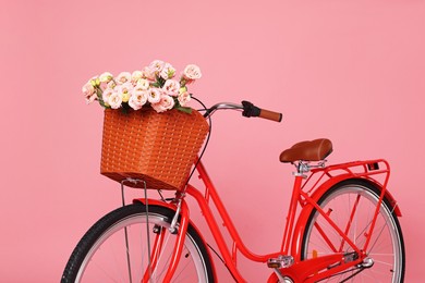 Photo of Bicycle with basket of beautiful flowers on pink background