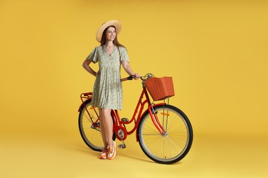 Photo of Smiling woman in hat and bicycle with basket on yellow background