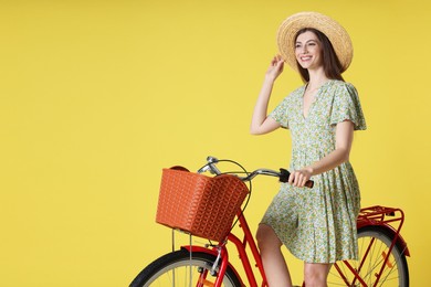 Photo of Smiling woman in hat posing on bicycle with basket against light green background. Space for text