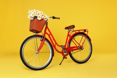 Photo of Bicycle with basket of beautiful flowers on yellow background