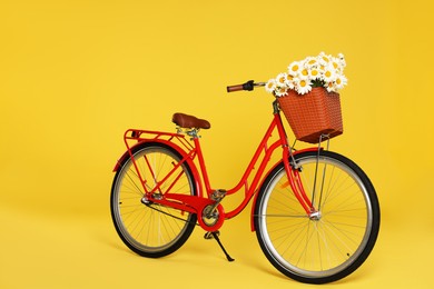 Photo of Bicycle with basket of beautiful flowers on yellow background