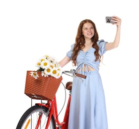 Photo of Smiling teenage girl taking selfie and bicycle with basket of flowers against white background