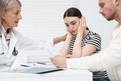 Photo of In vitro fertilization (IVF). Upset couple having consultation with doctor in reproductive clinic
