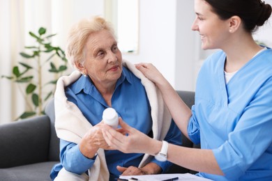 Photo of Nurse giving pills to senior woman indoors. Home health care service