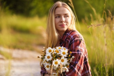 Photo of Beautiful woman with bouquet of wildflowers in meadow