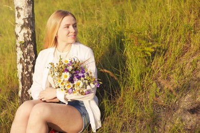Photo of Woman with bouquet of beautiful wildflowers outdoors on sunny day. Space for text