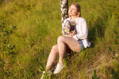 Photo of Woman with bouquet of beautiful wildflowers outdoors on sunny day