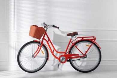 Photo of Red bicycle with basket near white wall indoors