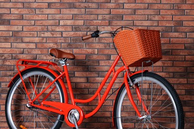 Photo of Red bicycle with basket near brick wall indoors