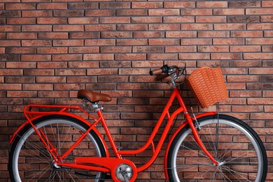 Photo of Red bicycle with basket near brick wall indoors. Space for text
