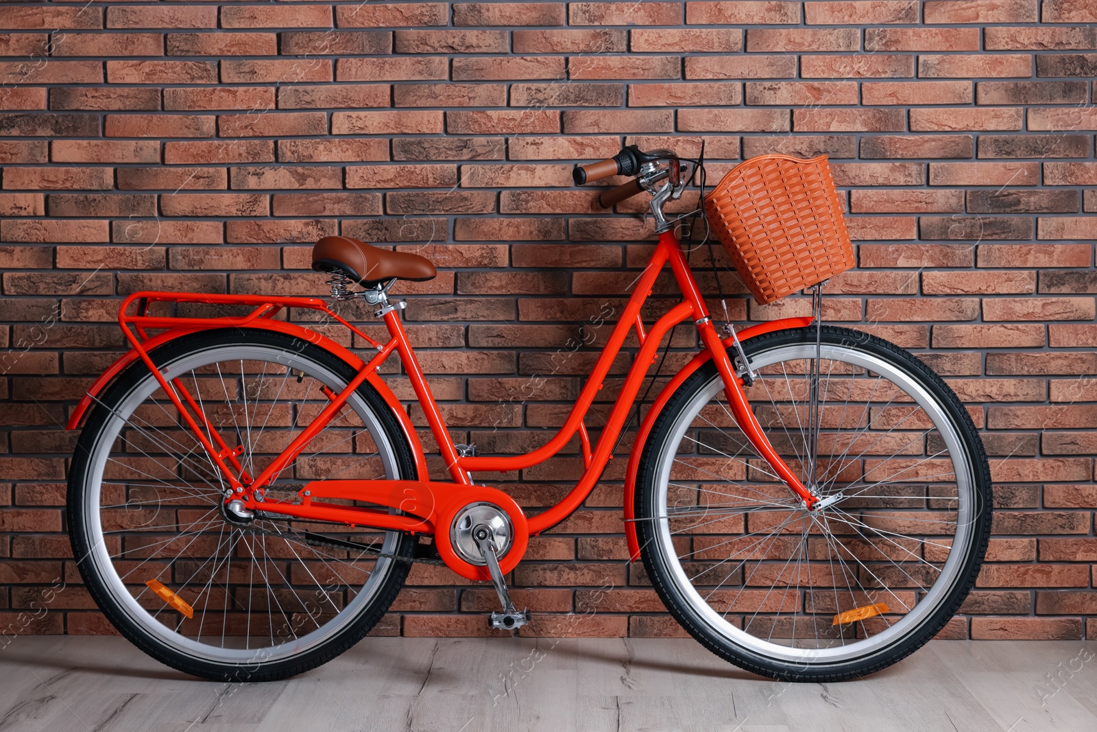 Red bicycle with basket near brick wall indoors Photo of Red bicycle with basket near brick wall indoors