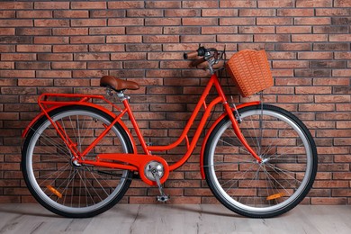 Photo of Red bicycle with basket near brick wall indoors