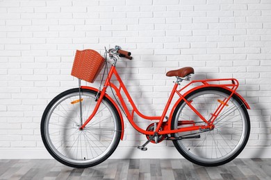 Photo of Red bicycle with basket near white brick wall indoors