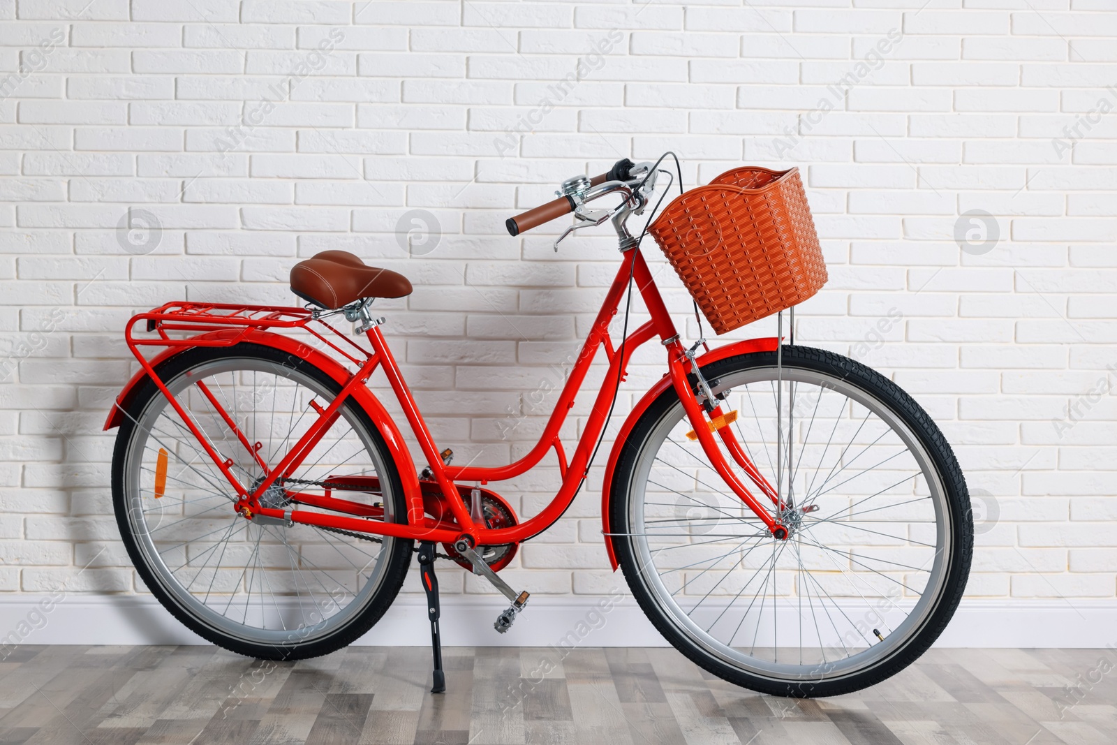 Red bicycle with basket near white brick wall indoors Photo of Red bicycle with basket near white brick wall indoors
