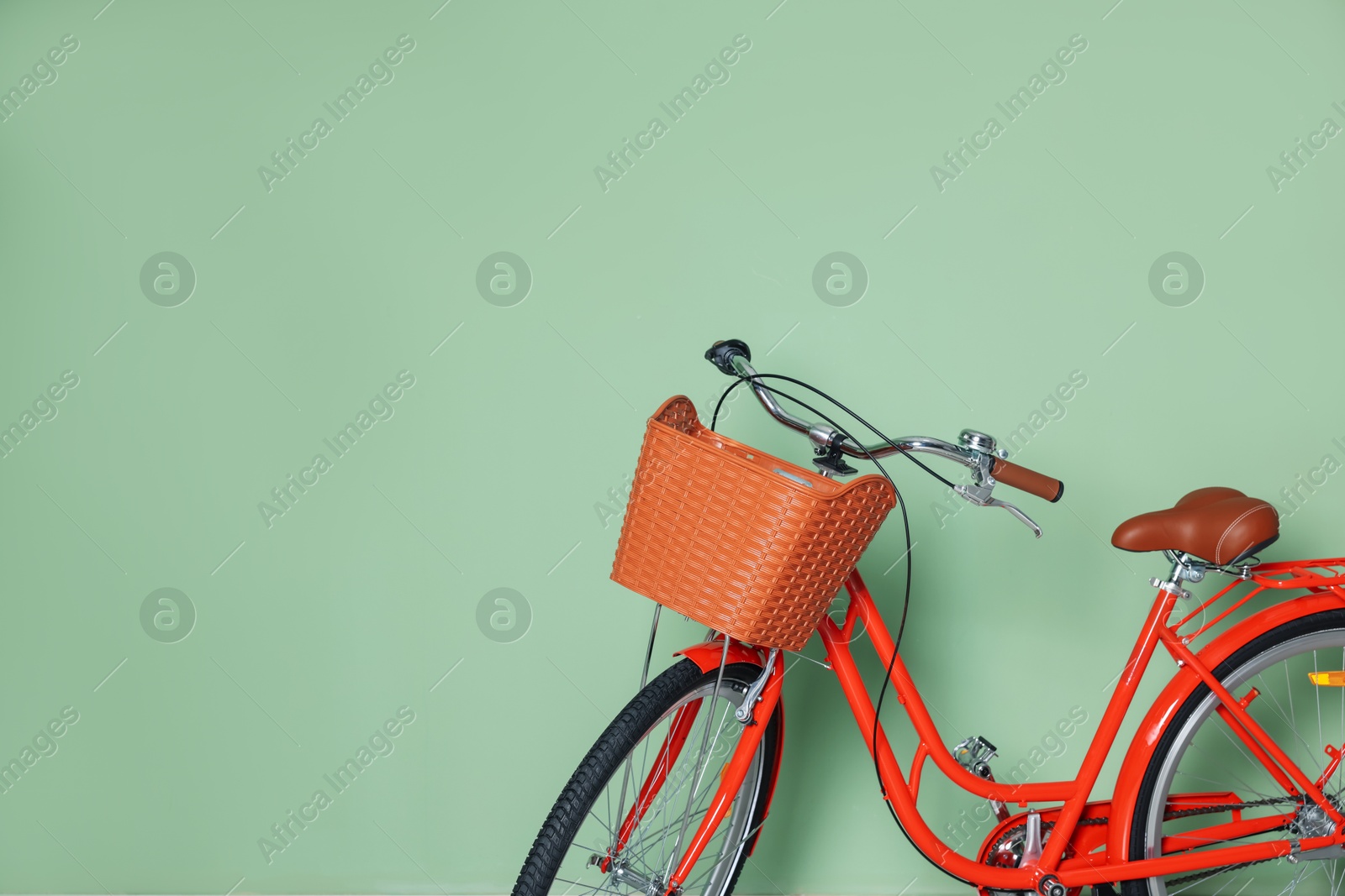 Red bicycle with basket near light green wall indoors. Space for text Photo of Red bicycle with basket near light green wall indoors. Space for text