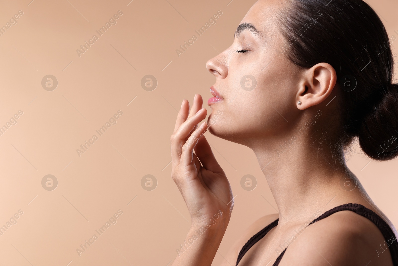 Young woman with lip balm on beige background, space for text Photo of Young woman with lip balm on beige background, space for text