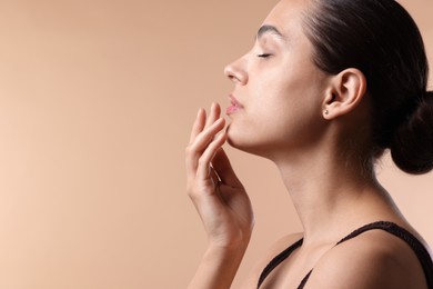 Photo of Young woman with lip balm on beige background, space for text