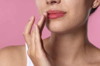 Photo of Young woman with lip balm on pink background, closeup