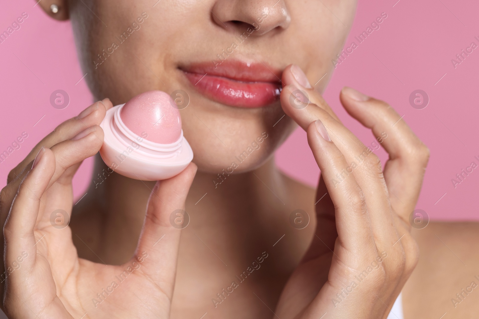 Young woman with lip balm on pink background, closeup Photo of Young woman with lip balm on pink background, closeup