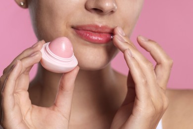 Photo of Young woman with lip balm on pink background, closeup