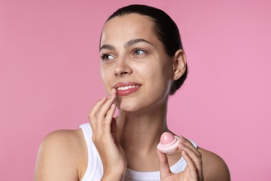 Photo of Young woman with lip balm on pink background