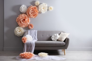Photo of Photo zone with stylish floral decor and sofa in studio