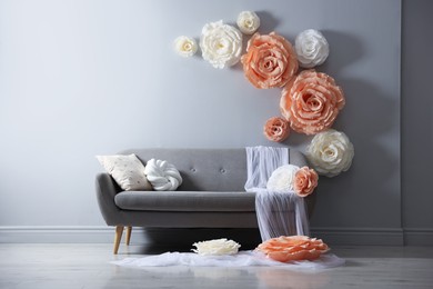 Photo of Photo zone with stylish floral decor and sofa in studio