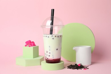 Photo of Tasty refreshing bubble tea and flower on pink background