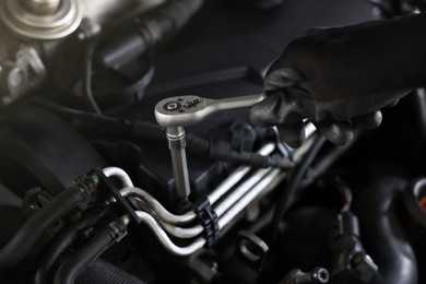 Photo of Auto parts. Professional mechanic with torque wrench fixing car indoors, closeup