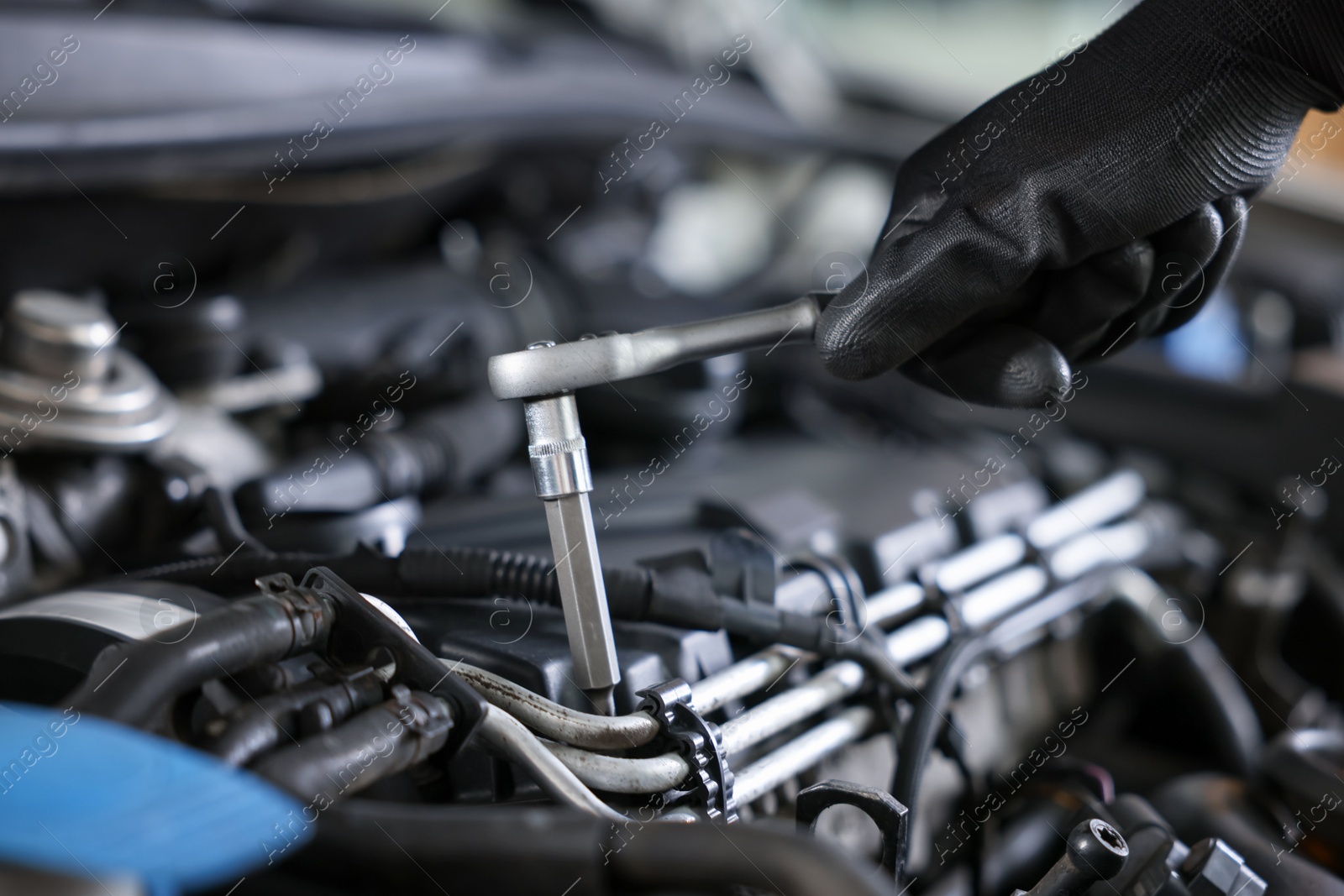 Auto parts. Professional mechanic with torque wrench fixing car indoors, closeup Photo of Auto parts. Professional mechanic with torque wrench fixing car indoors, closeup