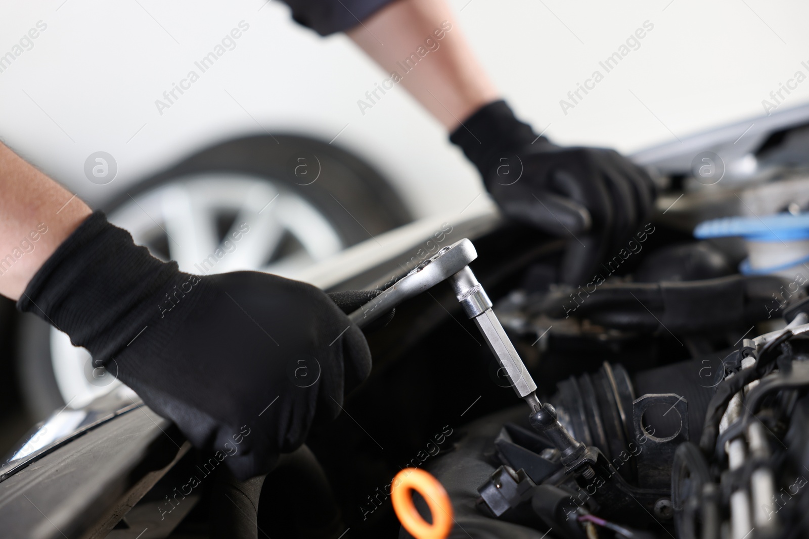 Auto parts. Professional mechanic with torque wrench fixing car indoors, closeup Photo of Auto parts. Professional mechanic with torque wrench fixing car indoors, closeup