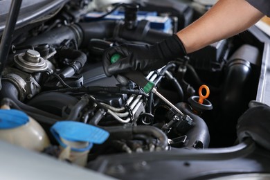 Photo of Auto parts. Professional mechanic with screwdriver fixing car indoors, closeup