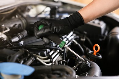 Photo of Auto parts. Professional mechanic with screwdriver fixing car indoors, closeup