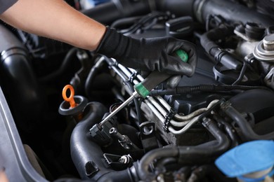 Photo of Auto parts. Professional mechanic with screwdriver fixing car indoors, closeup