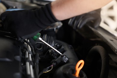 Photo of Auto parts. Professional mechanic with screwdriver fixing car indoors, closeup