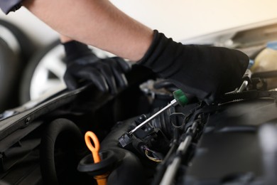 Photo of Auto parts. Professional mechanic with screwdriver fixing car indoors, closeup