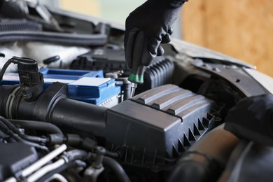 Photo of Auto parts. Professional mechanic with screwdriver fixing car indoors, closeup