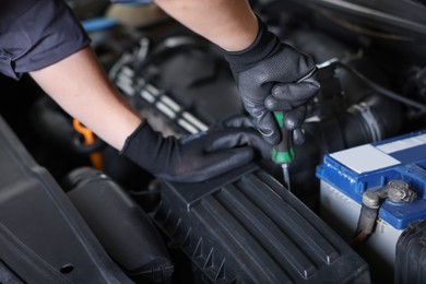 Photo of Auto parts. Professional mechanic with screwdriver fixing car indoors, closeup