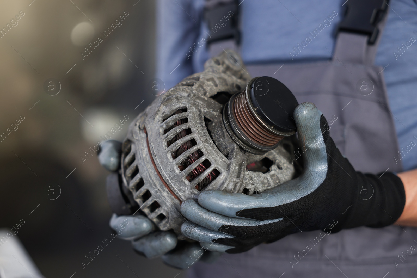 Auto part. Professional mechanic with alternator near indoors, closeup. Space for text Photo of Auto part. Professional mechanic with alternator near indoors, closeup. Space for text