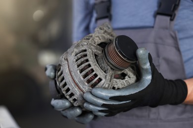 Photo of Auto part. Professional mechanic with alternator near indoors, closeup. Space for text