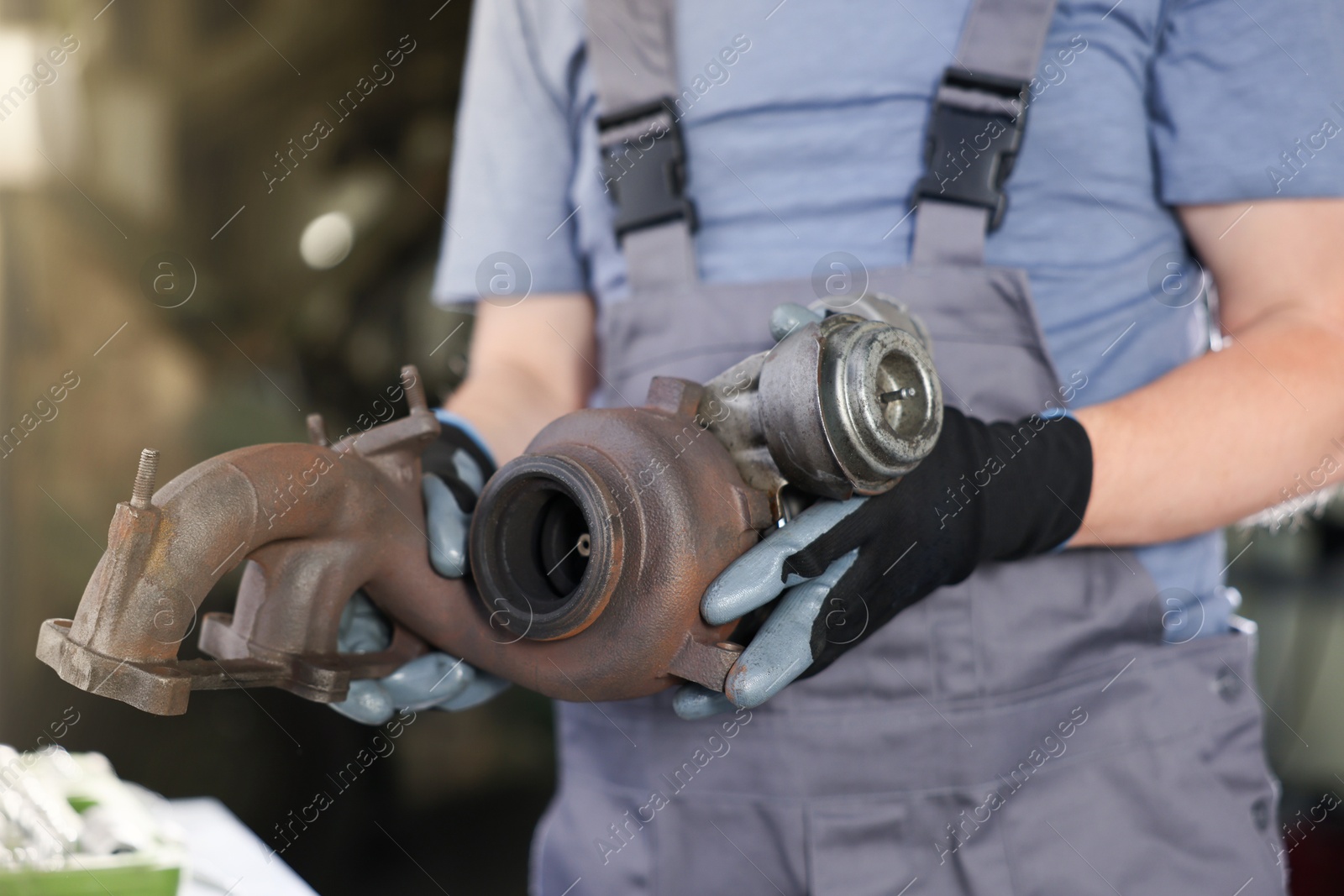 Auto part. Professional mechanic with turbocharger indoors, closeup Photo of Auto part. Professional mechanic with turbocharger indoors, closeup