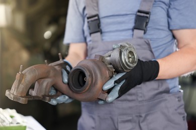 Photo of Auto part. Professional mechanic with turbocharger indoors, closeup