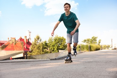 Photo of Happy man roller skating on city street. Space for text