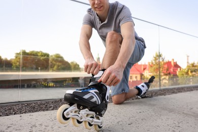 Photo of Man putting on roller skates outdoors, closeup